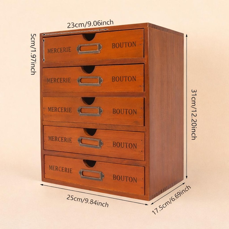 May include: A wooden five-drawer storage cabinet with a warm brown finish. Each drawer is labeled with the words "MERCERIE" and "BOUTON" and has a metal label holder. The cabinet measures 9.84 inches wide, 12.20 inches high, and 6.69 inches deep.