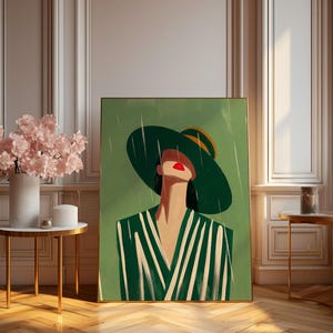 May include: An art print featuring a woman in a green hat and striped dress. The artwork has a green and white color scheme with a gold frame. The print is displayed in a room with a wooden floor and a small side table.