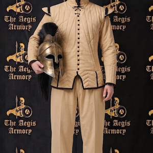 May include: A beige quilted doublet with black trim and a high collar, paired with matching beige trousers and black boots. The outfit is accompanied by a metallic bronze-toned helmet featuring a prominent black crest and a T-shaped face opening.
