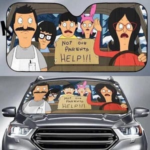 May include: A car sunshade featuring a cartoon family in a car, with the text "Not our parents HELP!!!" on a sign. The family members have exaggerated features and expressions, with one waving for help. The sunshade is placed over a car's windshield.