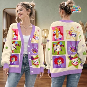 Pode incluir: Um cardigã de malha cor de creme com fecho de botões e acabamentos roxos. A peça é decorada com um padrão de patchwork colorido de personagens de desenhos animados, incluindo um bobo da corte, um coelho e dentes, sobre estrelas.