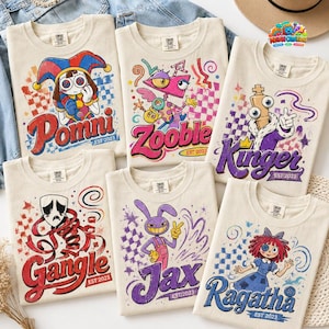 May include: Six cream-colored t-shirts featuring colorful graphic prints of cartoon characters. Each shirt displays a character name: Pomni, Zooble, Kinger, Gangle, Jax, or Ragatha, along with the text EST 2023, surrounded by checkered patterns and stars.