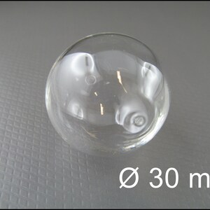May include: A clear glass sphere with a diameter of 30 mm. The sphere is smooth and reflective.