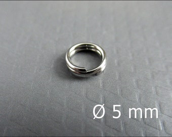 Könnte beinhalten: Ein silberner Sprungring mit einem Durchmesser von 5 mm. Der Ring ist aus Metall und ein gängiges Schmuckelement.