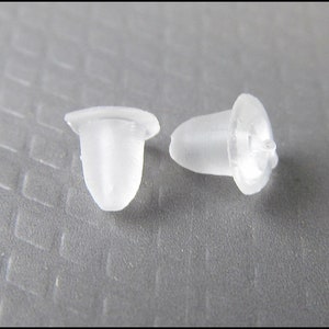 May include: Two clear plastic earring backs. The backs are shaped like a small cone with a flat top.