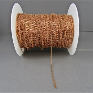 Könnte beinhalten: Eine Spule mit goldfarbener Kette, die um eine weiße Kunststoffspule gewickelt ist. Die Kette hängt von der Spule herunter und zeigt die Länge und Textur.