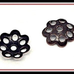 May include: Two metal flower-shaped bead caps with open circles. The bead caps are silver and copper in color.