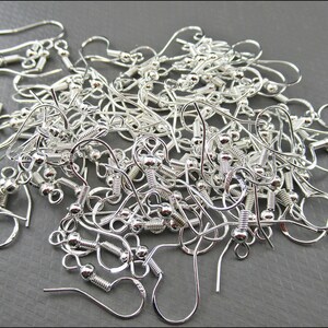 May include: A pile of silver-toned earring hooks with a small ball at the end of each hook.