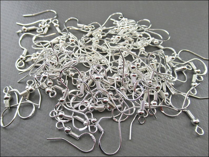 May include: A pile of silver-toned earring hooks with a small ball at the end of each hook.