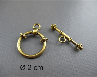 Puede incluir: Cierre de metal dorado con un anillo redondo y una barra de palanca. El anillo mide 2 cm de diámetro.