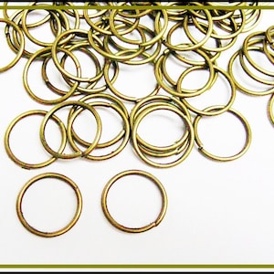 Könnte beinhalten: Ein Haufen goldfarbener Metall-Sprünge. Die Ringe sind klein und rund und auf einem weißen Hintergrund verstreut.