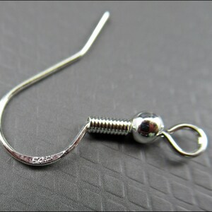 May include: Silver earring hook with a ball at the end and a spring-loaded closure. The hook is marked with "925" indicating it is made of sterling silver.