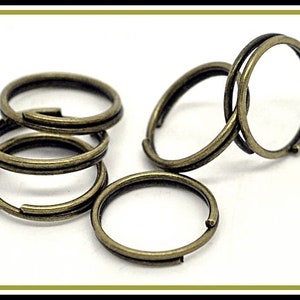 May include: Five antique gold-toned metal key rings. The key rings are stacked on top of each other.