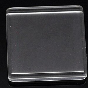 May include: A clear glass coaster with a beveled edge.
