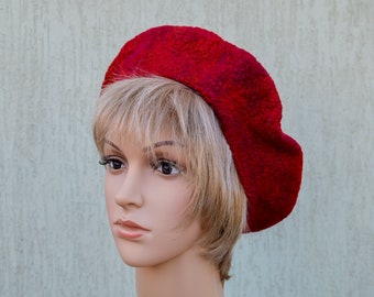 May include: A red beret made of felted wool. The beret is worn on a mannequin with short blonde hair.