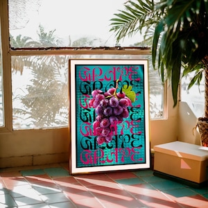 May include: A framed art print showing a bunch of purple grapes with green leaves. The word "GRAPE" is repeated vertically in black and pink lettering against a teal background. The frame is gold.