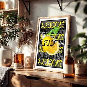 May include: A framed art print with a yellow lemon and a slice, and the word "LEMON" in a repeating pattern. The background is black and grey, and the frame is light brown.