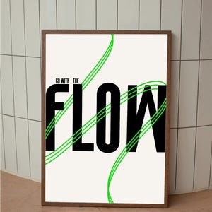 May include: A framed art print featuring the phrase "GO WITH THE FLOW" in large black letters. Green wavy lines are overlaid on the text. The print has a white background and a brown wooden frame.