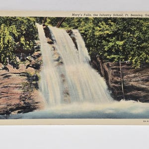 May include: Vintage postcard featuring Mary's Falls at the Infantry School in Ft. Benning, Georgia. The image shows a waterfall cascading over rocks, surrounded by lush green foliage. The postcard has a cream-colored border and the text "Mary's Falls, the Infantry School, Ft. Benning, Ga."