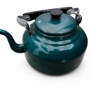 May include: A teal-colored kettle with a black handle and lid knob. The kettle has a rounded body, a curved spout, and a silver-colored handle. The kettle is likely made of metal and is designed for heating water.