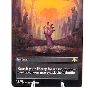 Peut inclure: Carte Magic: The Gathering &laquo;&nbsp;Entomb&nbsp;&raquo;. L'illustration montre une main sortant du sol dans un cimeti&egrave;re, avec un ciel orange. Le texte de la carte indique &laquo;&nbsp;Instant&nbsp;&raquo; et d&eacute;crit la fonction de la carte.