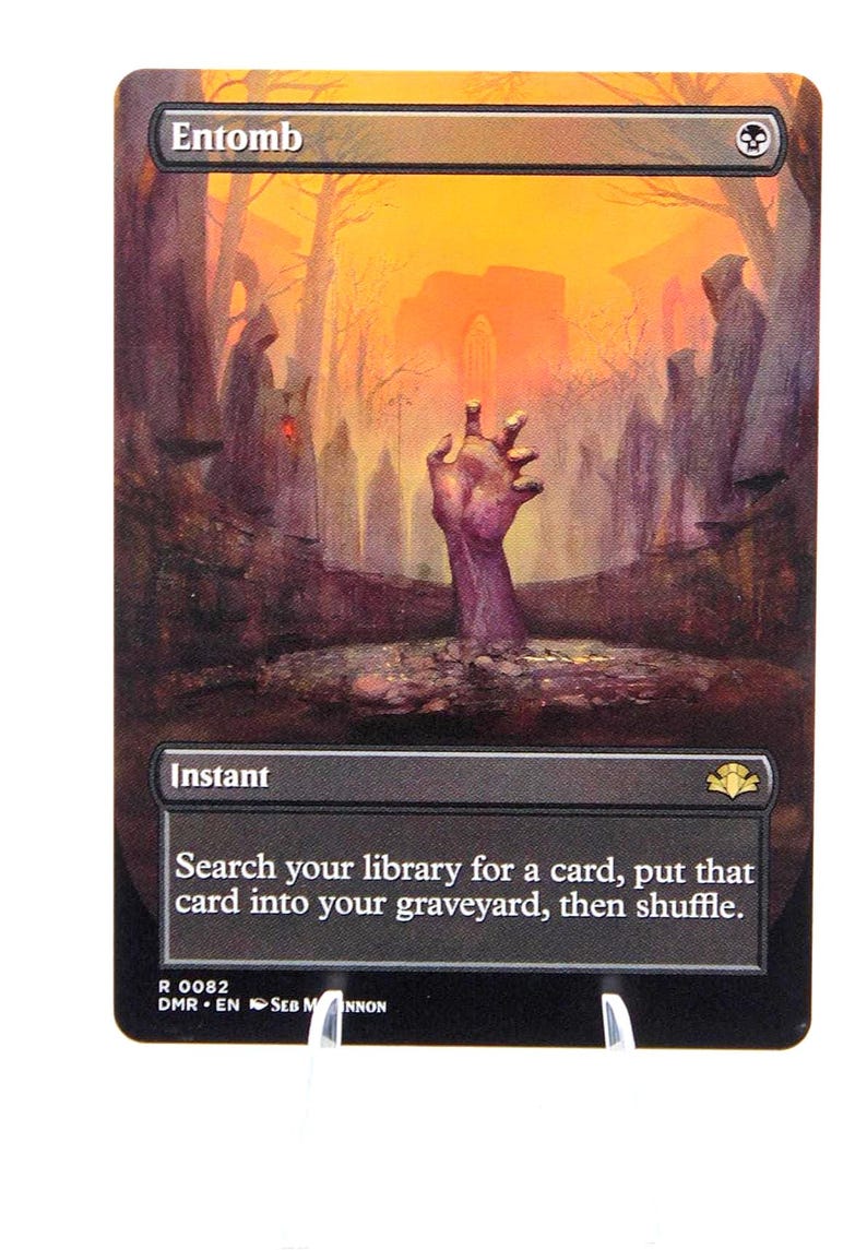 Peut inclure: Carte Magic: The Gathering &laquo;&nbsp;Entomb&nbsp;&raquo;. L'illustration montre une main sortant du sol dans un cimeti&egrave;re, avec un ciel orange. Le texte de la carte indique &laquo;&nbsp;Instant&nbsp;&raquo; et d&eacute;crit la fonction de la carte.