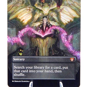 Peut inclure: Carte Magic: The Gathering &laquo;&nbsp;Demonic Tutor&nbsp;&raquo;. L'illustration montre une sorci&egrave;re lisant un livre, avec de l'&eacute;nergie rose et une figure d&eacute;moniaque. Le texte de la carte dit &laquo;&nbsp;Cherchez dans votre biblioth&egrave;que une carte, mettez cette carte dans votre main, puis m&eacute;langez&nbsp;&raquo;.