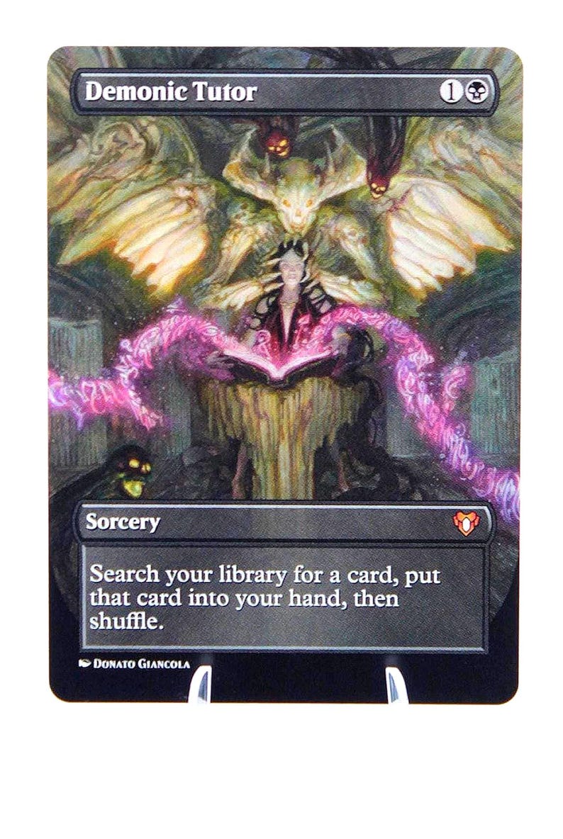 Peut inclure: Carte Magic: The Gathering &laquo;&nbsp;Demonic Tutor&nbsp;&raquo;. L'illustration montre une sorci&egrave;re lisant un livre, avec de l'&eacute;nergie rose et une figure d&eacute;moniaque. Le texte de la carte dit &laquo;&nbsp;Cherchez dans votre biblioth&egrave;que une carte, mettez cette carte dans votre main, puis m&eacute;langez&nbsp;&raquo;.