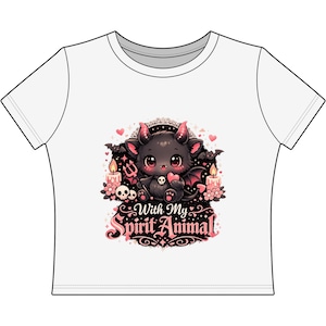 May include: White t-shirt featuring a cartoon illustration of a black bat with red horns and wings, holding a heart. The design includes candles, skulls, and the text "With My Spirit Animal" in pink and black.