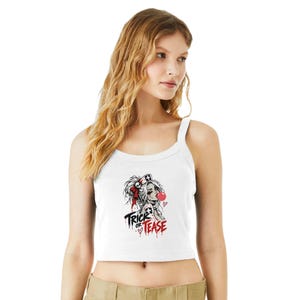 Puede incluir: Una camiseta de tirantes blanca con una ilustración gráfica de una enfermera con un lazo rojo, soplando una burbuja rosa, y el texto "TRICK OR TEASE" en letras rojas y negras con gotas de sangre y pequeños corazones en el centro.