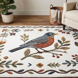 Könnte beinhalten: Rechteckiger weißer Teppich mit einem detaillierten Vogel- und Blumendesign. Der Vogel sitzt auf einem Ast, umgeben von Blättern, Blumen und Beeren. Der Rand weist ein sich wiederholendes Muster aus Ranken und Blättern auf.