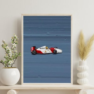 May include: A framed art print featuring a red and white Formula 1 race car with the Marlboro logo on the side, set against a textured blue background. The car has a yellow-helmeted driver and black wheels, presented in a simple wooden frame.