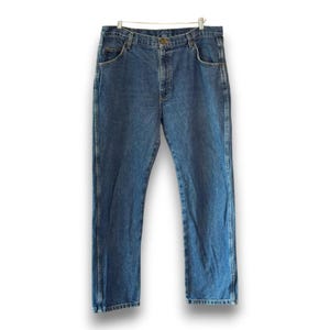 May include: Blue denim jeans with a classic five-pocket design. The jeans are hanging on a hanger against a white background. The jeans have a button and zipper closure, and belt loops. The denim is a medium wash.