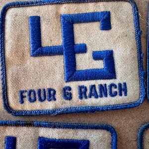 Puede incluir: Parche rectangular crema con un diseño bordado en azul. El diseño presenta las letras "4G" y las palabras "FOUR G RANCH" en azul. El parche tiene un borde azul.