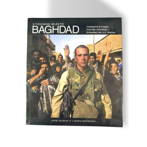 May include: A hardcover book titled A Thousand Miles to Baghdad: Impressions & Images From Two Journalists Embedded with U.S. Marines by Hayne Palmour IV and Darrin Mortenson. The cover features a photograph of a soldier in camouflage gear.