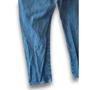 May include: Close-up of light blue denim jeans. The jeans have a classic, straight-leg fit and a medium wash. The fabric shows subtle fading and wear, suggesting a vintage or well-loved appearance. The image highlights the texture and color of the denim.