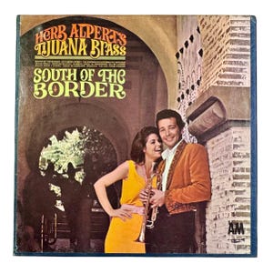 May include: Vintage vinyl record album cover for Herb Alpert's Tijuana Brass, titled "South of the Border." The cover features a couple, a woman in a yellow dress and a man in a brown jacket, with a trumpet. The album's title is in large, bold letters.