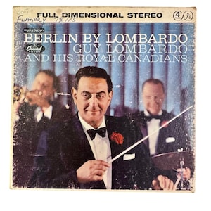 May include: Vintage album cover for "Berlin by Lombardo" by Guy Lombardo and His Royal Canadians. The cover features a man in a tuxedo holding a conductor's baton, with two other men in the background. The album is a full dimensional stereo.