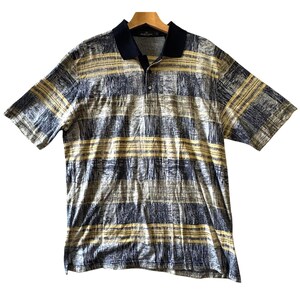 May include: A short-sleeve polo shirt featuring a horizontal striped pattern in shades of navy blue, yellow, and white with a textured, brushstroke-like effect. The garment has a solid navy blue collar and a buttoned placket at the neckline.