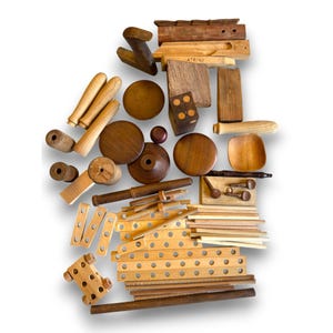 Puede incluir: Una colección de varias piezas de juguetes de madera, incluyendo clavijas, ruedas, bloques y otras formas geométricas. Las piezas son en tonos de marrón claro y oscuro, con un acabado de veta de madera natural. Algunas piezas tienen tornillos y otros herrajes.