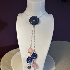 May include: A white ceramic mug with a black handle and the text "But First, Coffee" in a black, handwritten-style font. The mug is on a white surface.