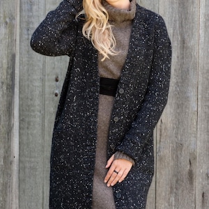 Woman wearing long Irish Donegal wool cardigan outdoors in autumn setting, black