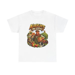 Puede incluir: Camiseta blanca con una ilustración colorida. El diseño muestra a un hombre sosteniendo una cerveza, rodeado de manzanas, un perro y un tractor. El texto "Alright My Luvver" se muestra encima del hombre.