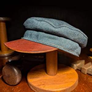 May include: A white ceramic mug with a black handle and the text "But First, Coffee" in a bold, black font. The mug is set against a blurred background, suggesting a cozy setting.