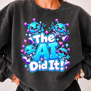 Puede incluir: Una sudadera de cuello redondo gris carbón con un estampado gráfico de cuatro robots azules de dibujos animados y el texto The AI Did It! en letras grandes, negritas, azul claro y blancas, rodeado de pequeños corazones rosas y estrellas azules.