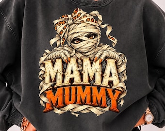 Op de afbeelding: Een antracietgrijze sweater met ronde hals en een afbeelding van een mummie met een strik met luipaardprint. De mummie heeft zichtbare ogen en klauwachtige vingers. Onder de mummie staat de tekst MAMA MUMMY in grote, oranje en crèmekleurige letters.