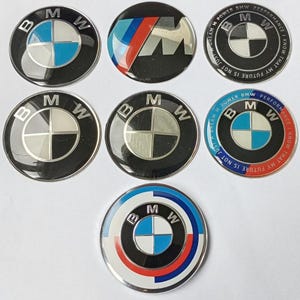 Può includere: Una collezione di sette distintivi con l'emblema BMW. I distintivi presentano il logo BMW in vari design, tra cui il classico quadrante blu e bianco e il logo BMW M. Alcuni distintivi hanno testo sul bordo, come "BMW Performance".