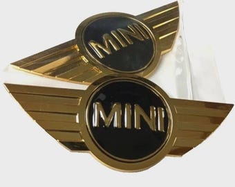 2 stemmi con logo MINI, color oro, per cofano e bagagliaio.