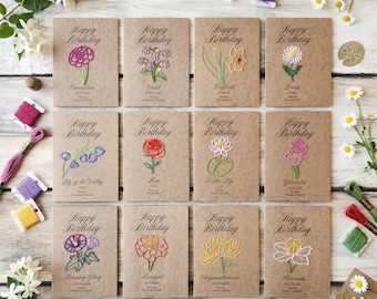May include: Twelve rectangular kraft paper birthday cards featuring embroidered birth flowers for each month. Each card displays the text Happy Birthday, the flower name, and the month. The cards are arranged in a grid with colorful embroidery thread.
