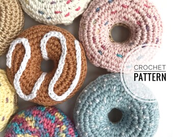 May include: A collection of colorful, crocheted donuts. The donuts are in various colors, including brown, pink, and blue, with white icing and sprinkles. The text "CROCHET PATTERN" is visible in the image.